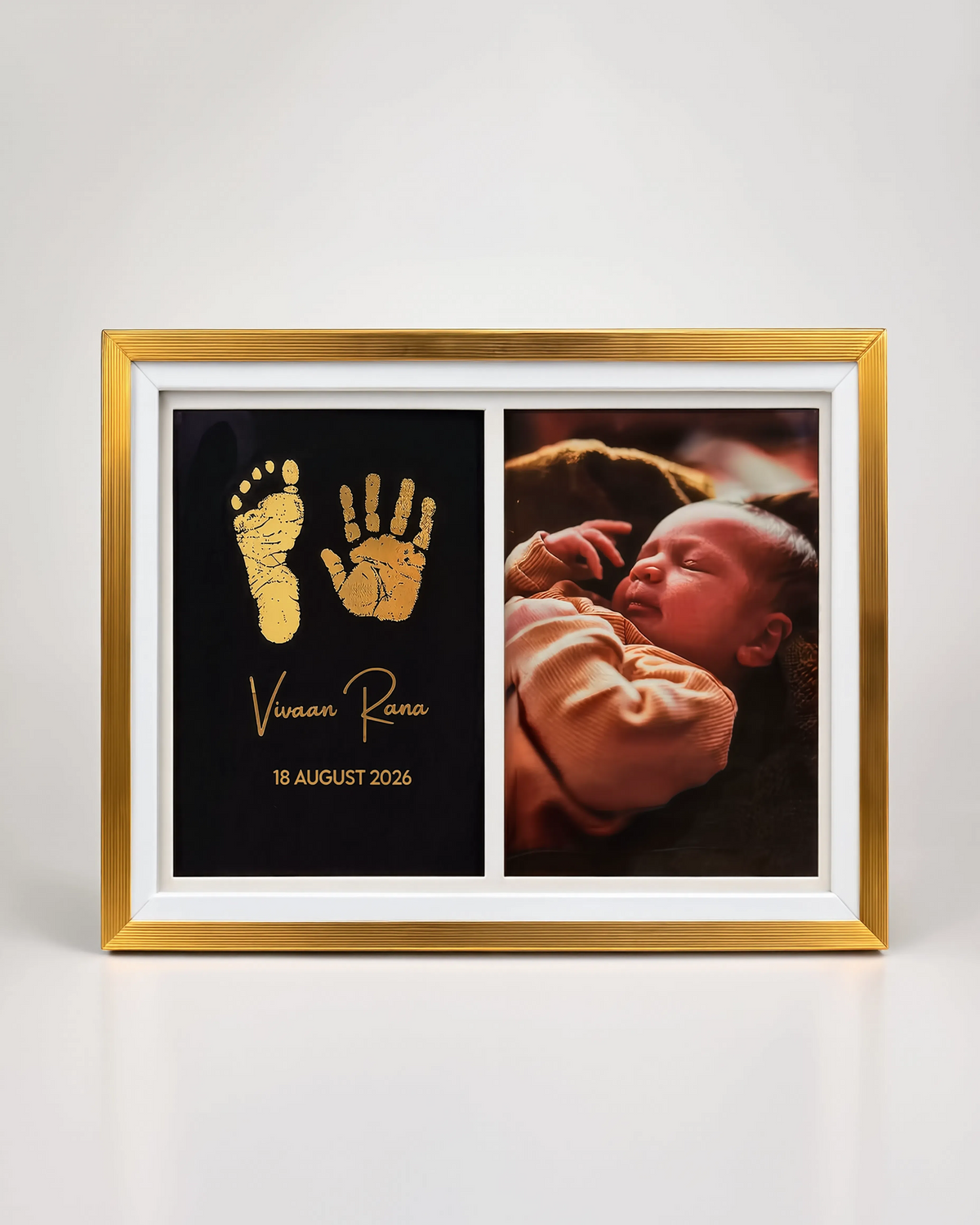A custom framed baby keepsake print with a gold frame and white mat. The left panel is black with a gold baby footprint and handprint, along with the name 'Vivian Rana' and date '18 AUGUST 2026'.