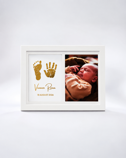 A white rectangular keepsake photo frame on a light gray background. The left side features gold baby footprints and handprints with the name 'Vivian Rana' and the date '18 AUGUST 2026' in gold script.