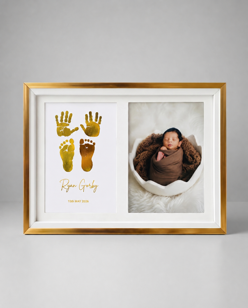 A gold and white double-sided framed baby keepsake photo frame. The left side features a white background with gold foil baby handprints and footprints and the personalized name 'Ryan Grady' in gold script.