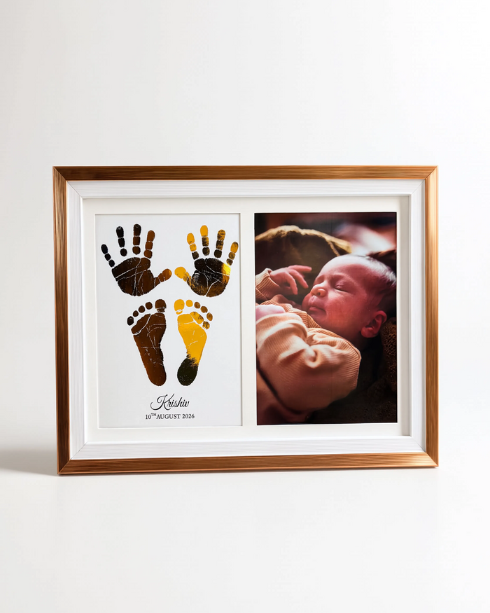 A custom framed baby keepsake photo print with a gold frame, featuring a white mat with black and yellow baby footprints on the left and a photo of a sleeping baby on the right.