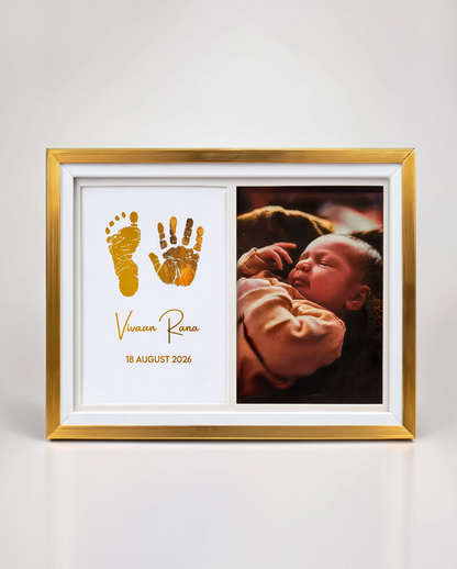 A personalized gold picture frame with a white mat, featuring a baby photo on the right and gold baby footprints and handprints with the name 'Vivian Rona' and date '18 August 2026' on the left, shown on a clean white background.