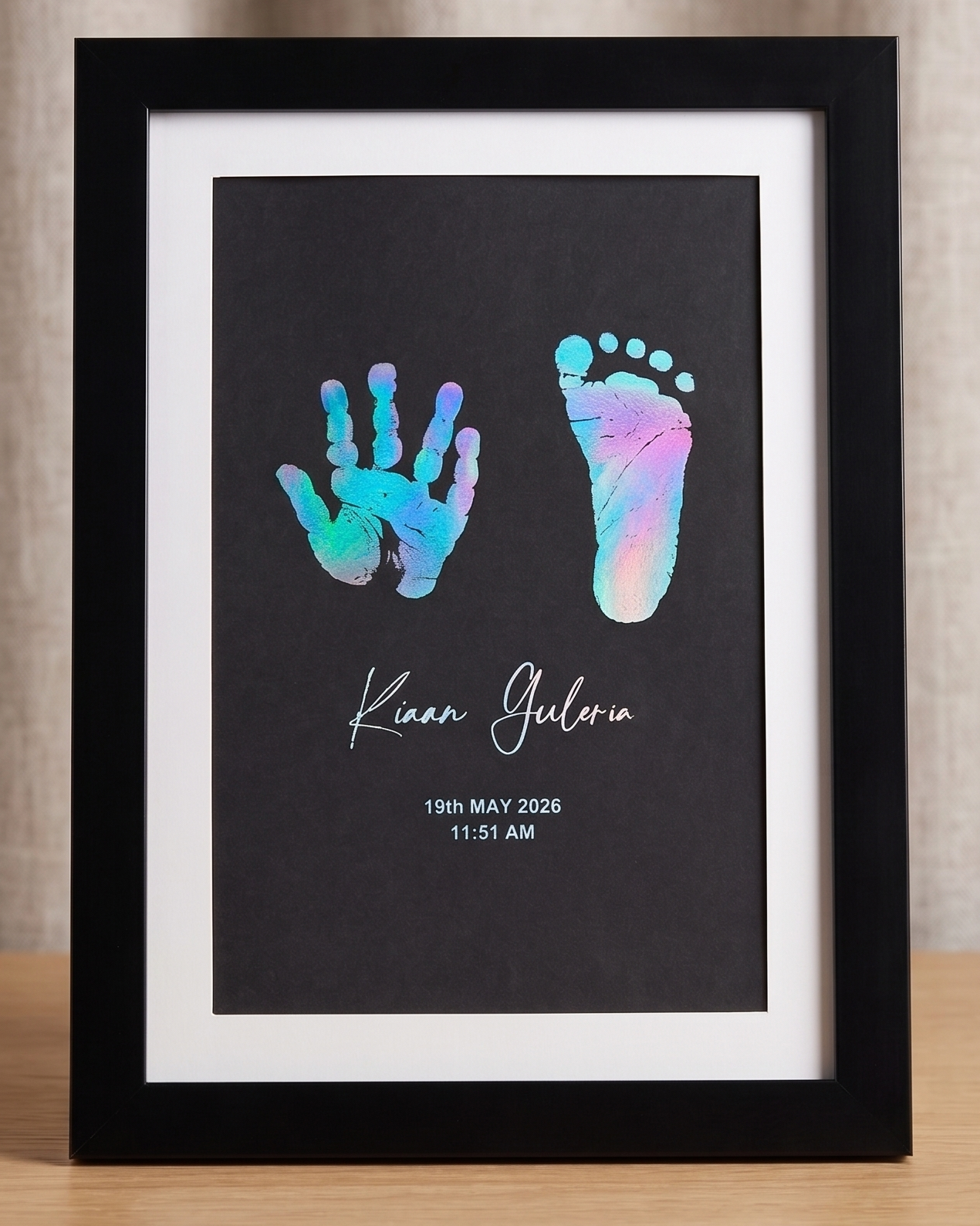 Framed artwork with rainbow foiled hand and footprints on a black background.
